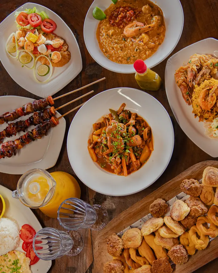 Mesa servida con guacho de mariscos, mondongo, pinchos, camarones y hojaldres