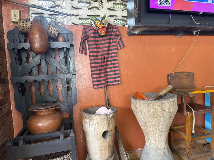 Decoración folclórica: máscara tallada, camisilla, ollas de barro y tambores