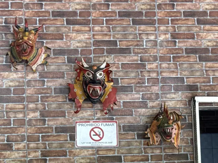 Máscaras de diablico colgadas en la pared de ladrillo