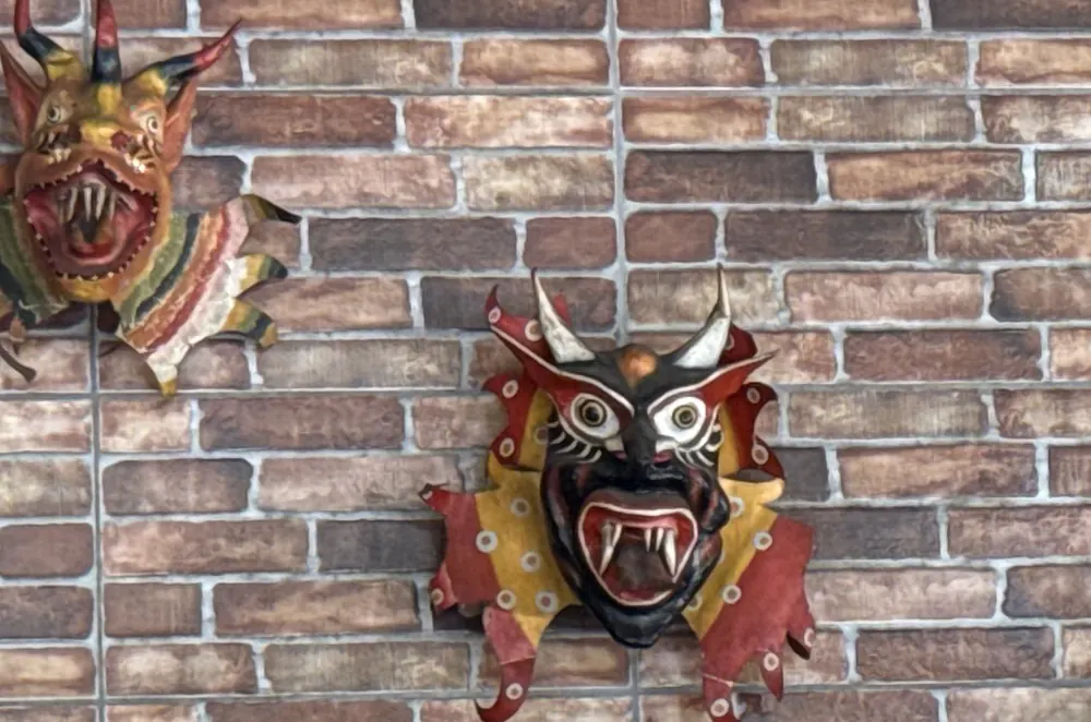 Máscaras de diablico talladas colgadas en la pared de ladrillo del comedor